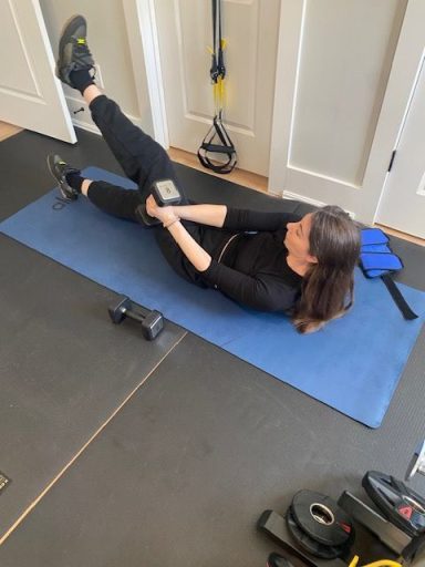 Zero Commute Person performing a stretching exercise on a blue mat in a gym setting.